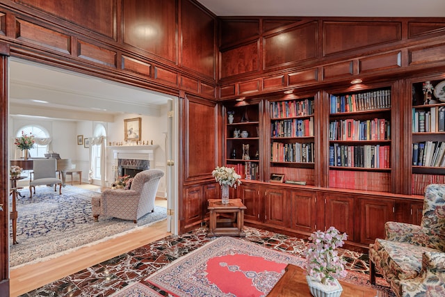 living area with a high end fireplace, ornamental molding, a decorative wall, and built in shelves
