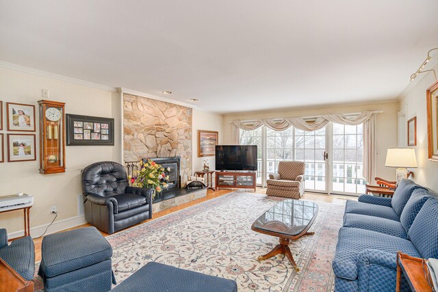 living area with baseboards, ornamental molding, wood finished floors, and a fireplace
