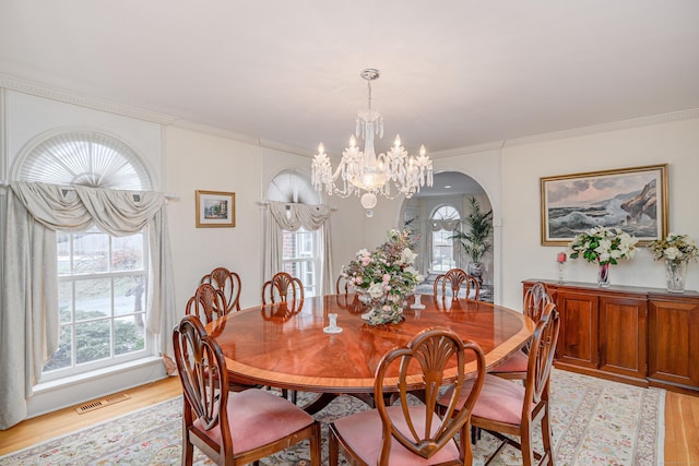 dining room with arched walkways, visible vents, a chandelier, and light wood finished floors