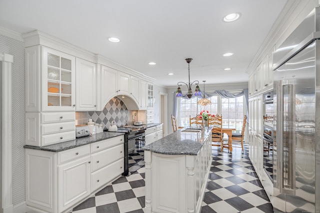 kitchen featuring a kitchen island, white cabinets, glass insert cabinets, light floors, and stainless steel appliances
