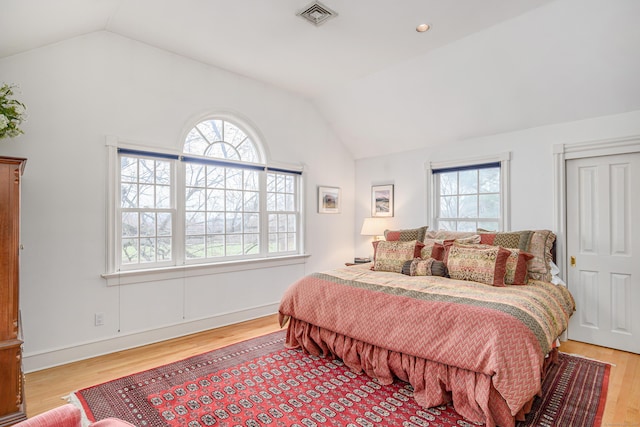bedroom with visible vents, multiple windows, light wood-style flooring, and lofted ceiling