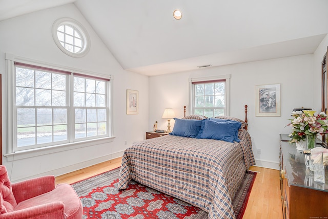 bedroom featuring light wood-style floors, high vaulted ceiling, baseboards, and visible vents