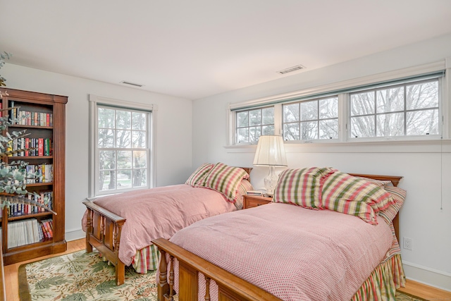 bedroom featuring visible vents, multiple windows, and wood finished floors
