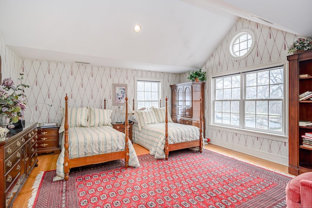 bedroom featuring wallpapered walls, wood finished floors, and lofted ceiling
