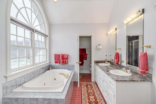 full bath with lofted ceiling, toilet, a jetted tub, tile patterned floors, and a sink