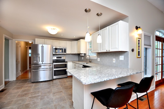 5 Middle Dr, Windsor Locks, CT 06096 - kitchen featuring appliances with stainless steel finishes, a peninsula, plenty of natural light, and light stone countertops