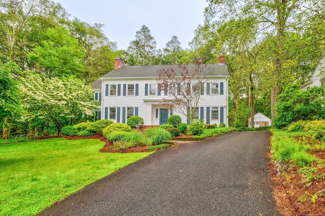 64 Blake Rd, Hamden, CT 06517 - colonial house featuring a chimney, a front yard, view of wooded area, and a garage