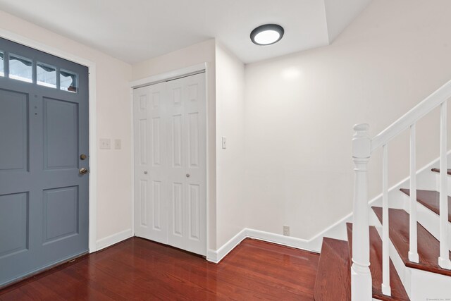 entryway featuring baseboards, stairs, and dark wood-style floors
