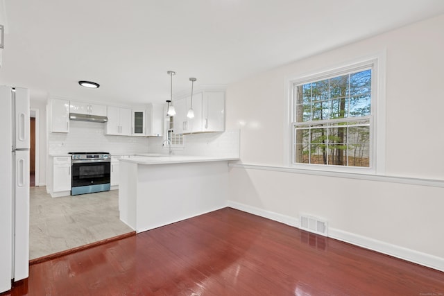 kitchen with stainless steel electric range oven, visible vents, freestanding refrigerator, under cabinet range hood, and white cabinetry