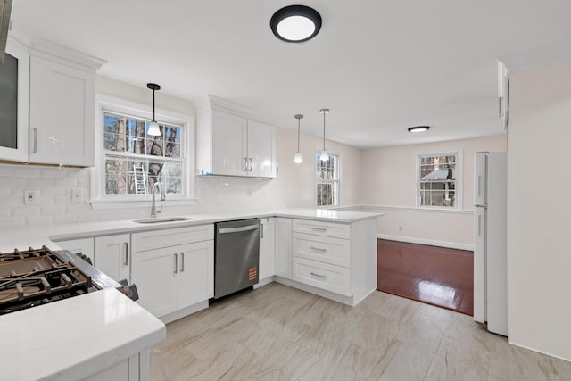 kitchen featuring stainless steel dishwasher, freestanding refrigerator, tasteful backsplash, a peninsula, and a sink
