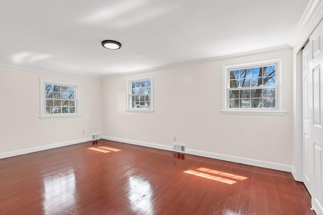 interior space featuring visible vents, ornamental molding, baseboards, and wood finished floors