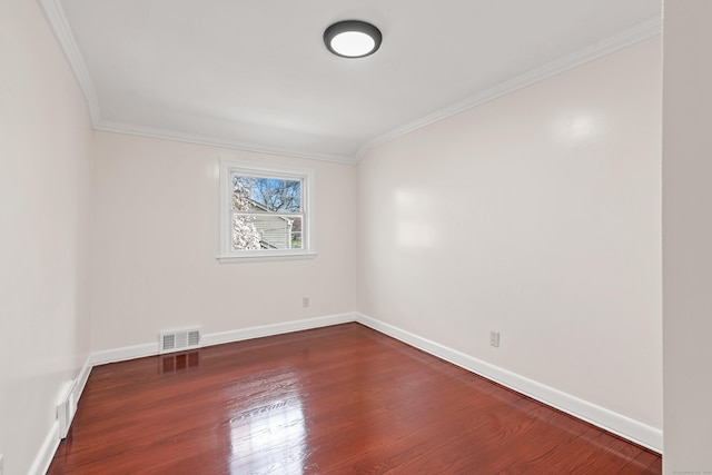 unfurnished room featuring visible vents, baseboards, ornamental molding, and wood finished floors