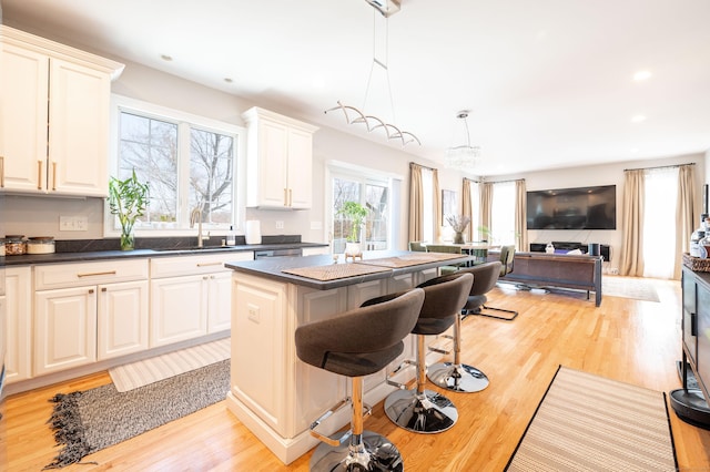 kitchen featuring dark countertops, light wood-style flooring, a sink, and a breakfast bar area