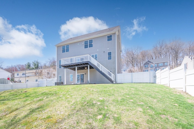 back of property with a fenced backyard, a wooden deck, a yard, and stairs