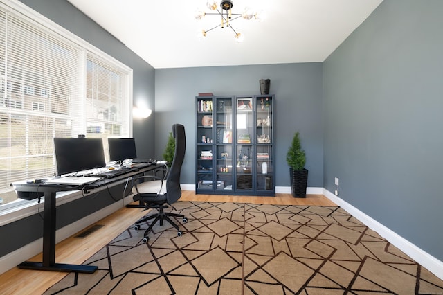 home office featuring visible vents, baseboards, wood finished floors, and a notable chandelier