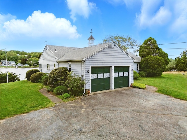 27 Wilbur Rd, Stonington, CT 06378 - view of side of home featuring a lawn, asphalt driveway, an attached garage, and a shingled roof
