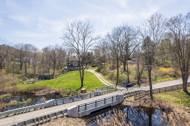 view of community featuring fence, a yard, and a water view