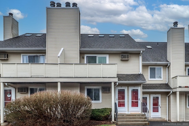 view of front facade with a chimney, a shingled roof, and a balcony
