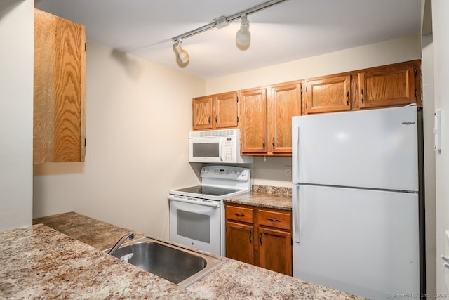 kitchen with a sink, light countertops, white appliances, and brown cabinets