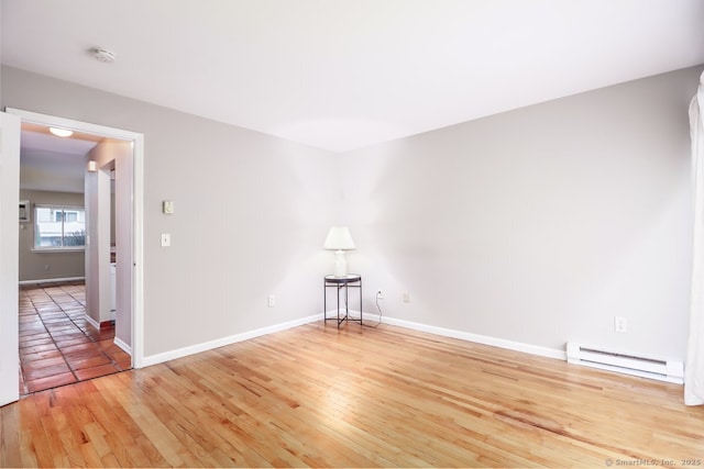 unfurnished room featuring light wood-style floors, a baseboard radiator, and baseboards