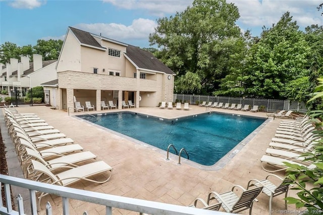 community pool with a patio area and fence