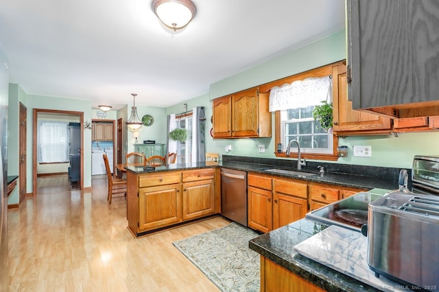 kitchen with a sink, brown cabinetry, stainless steel dishwasher, and a peninsula
