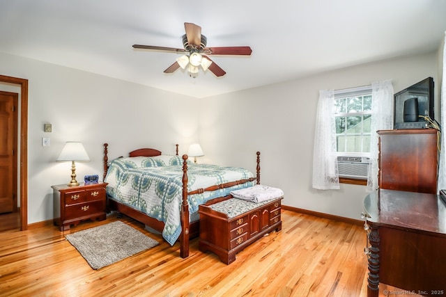 bedroom with cooling unit, light wood-style flooring, baseboards, and ceiling fan