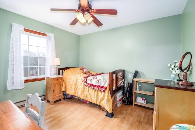 bedroom with light wood-style floors, a baseboard radiator, and a ceiling fan