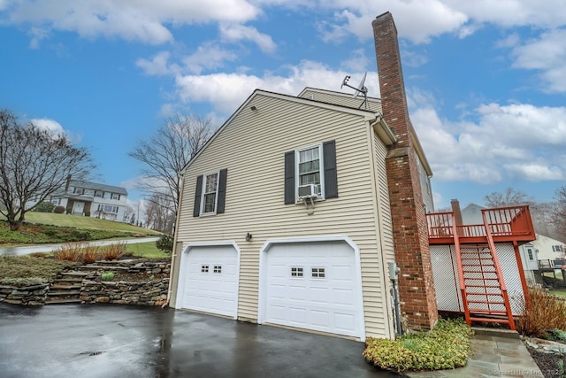 view of side of home featuring a chimney, a garage, aphalt driveway, and stairs