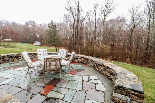 view of patio / terrace featuring outdoor dining area, an outdoor structure, and a storage unit