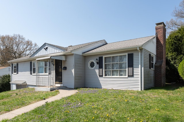 single story home featuring a chimney, a shingled roof, and a front lawn