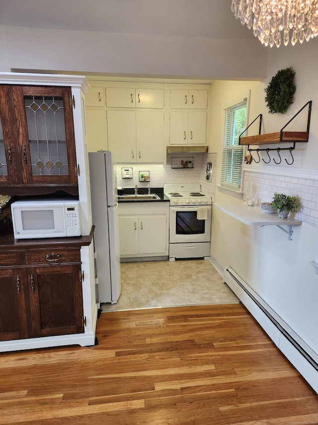 kitchen featuring white appliances, a baseboard radiator, a sink, and backsplash
