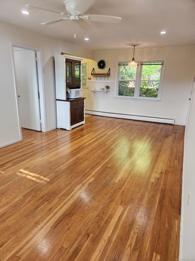 unfurnished living room featuring baseboard heating, light wood finished floors, a ceiling fan, and recessed lighting