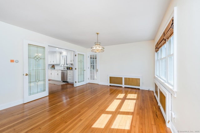 186 Isinglass Rd, Shelton, CT 06484 - unfurnished dining area with light wood-style floors, radiator, baseboards, and a notable chandelier