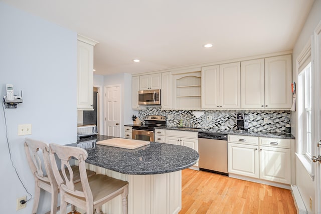 39 Overlook Dr, New Milford, CT 06776 - kitchen featuring backsplash, appliances with stainless steel finishes, a peninsula, a breakfast bar, and light wood-style flooring
