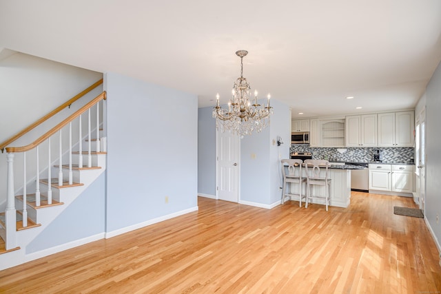 39 Overlook Dr, New Milford, CT 06776 - kitchen with an inviting chandelier, a kitchen breakfast bar, stainless steel appliances, decorative backsplash, and light wood-type flooring