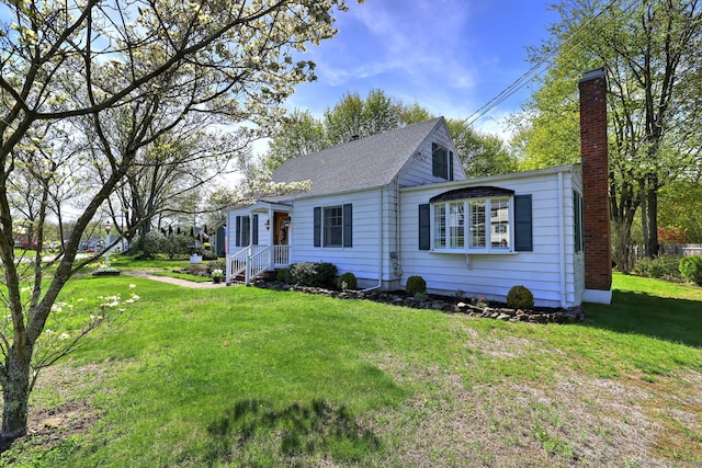 view of front of house featuring a shingled roof, a chimney, and a front yard