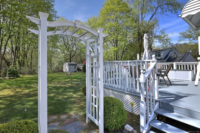 wooden deck with a storage unit, an outdoor structure, and a yard
