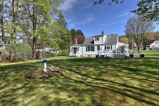 rear view of property with roof with shingles, a wooden deck, a yard, and a chimney