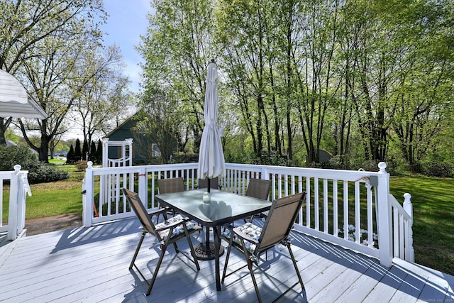 wooden deck with a lawn and outdoor dining space