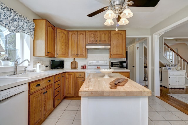 kitchen featuring a healthy amount of sunlight, a ceiling fan, a sink, under cabinet range hood, and white appliances