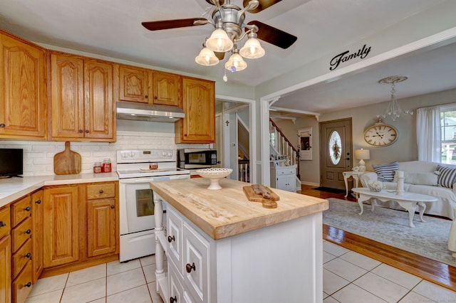 kitchen featuring light tile patterned flooring, electric stove, stainless steel microwave, open floor plan, and under cabinet range hood