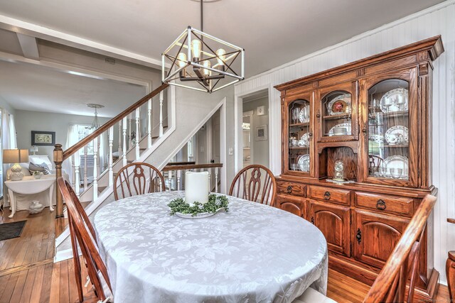 dining space with an inviting chandelier, stairs, and hardwood / wood-style flooring