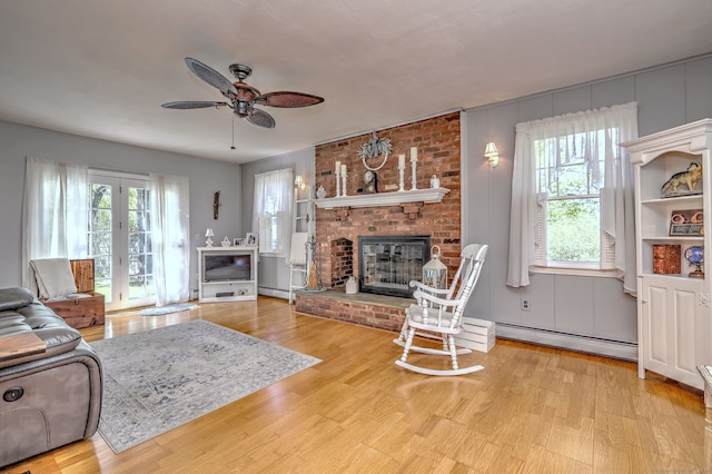 living room featuring a ceiling fan, a baseboard heating unit, and a wealth of natural light