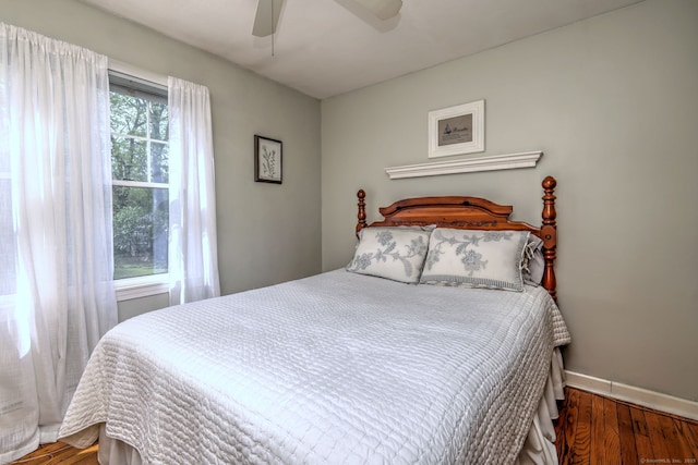bedroom with baseboards, ceiling fan, and wood finished floors