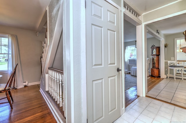 corridor with baseboards, plenty of natural light, a baseboard heating unit, and wood finished floors