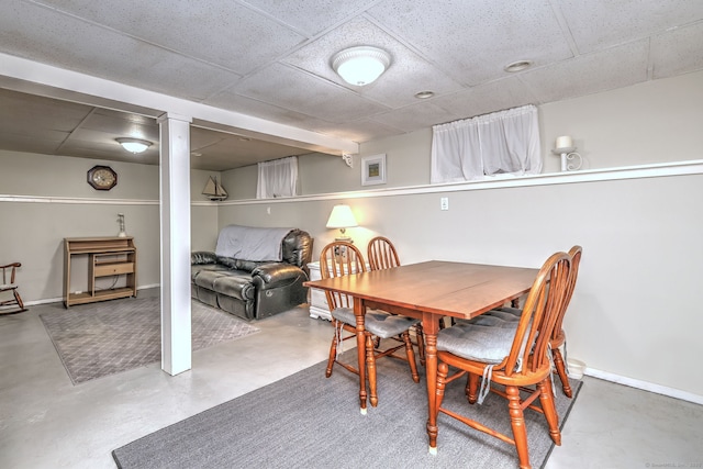 dining space featuring baseboards, concrete floors, and a paneled ceiling