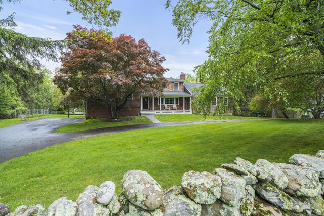 27 Blue Ribbon Dr, Westport, CT 06880 - view of front of home featuring a porch, a chimney, a front lawn, brick siding, and asphalt driveway