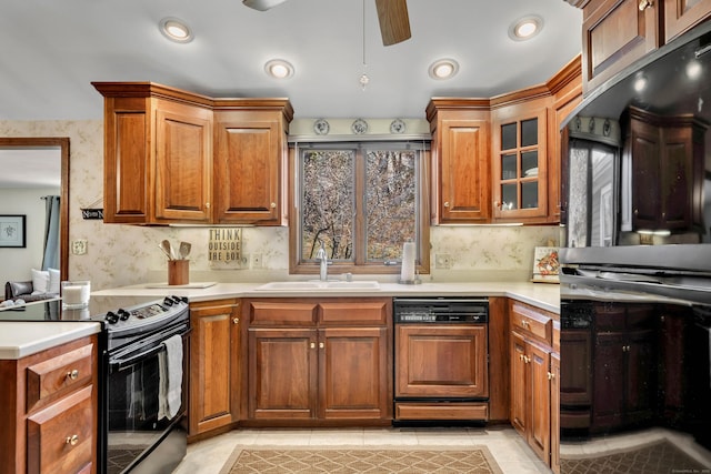 kitchen with a sink, light countertops, black / electric stove, wallpapered walls, and paneled dishwasher