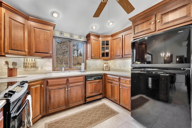 kitchen featuring black fridge, a sink, brown cabinetry, stove, and paneled dishwasher